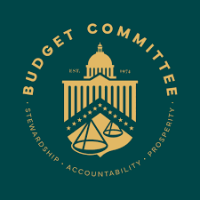 Circular Budget Committee logo featuring a domed capitol building above scales of justice, with the motto 'Stewardship, Accountability, Prosperity' around and EST. 1974.
